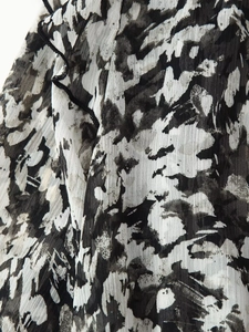 Detail of ruffle hem with black trim on abstract black and white print mini dress