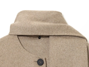 Close-up of beige wool coat lapel with a black resin button and woven texture detail