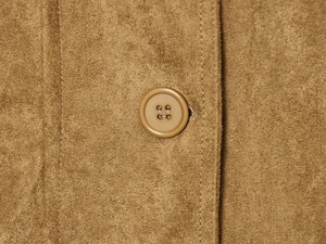 Macro detail of brown suede jacket showing resin button and fine double-stitched seams
