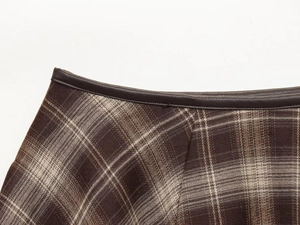 Détail d'une jupe écossaise taille haute en laine marron avec passepoil en cuir à la taille
