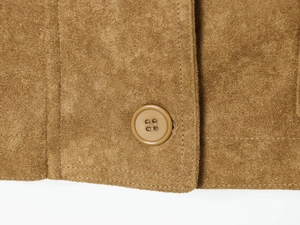 Close-up of brown suede fabric showing detailed stitching and tonal four-hole resin button