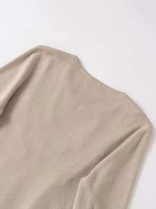 Detail of light beige knit sweater showing ribbed texture and shoulder seam craftsmanship