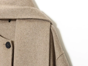 Close-up of beige wool coat featuring a large lapel and premium dark round button details
