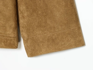 Macro shot of premium suede texture and precise horizontal stitching on a brown jacket