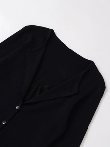 Close-up of black V-neck knit cardigan featuring elegant lace splicing and dark buttons