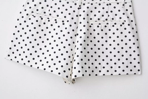 Détails des poches arrière et passants de ceinture sur un short blanc à pois noirs