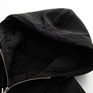 Détail de veste noire à capuche avec doublure matelassée en losanges et zip métallique