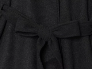 Dettaglio del cappotto a mantella con collo alto che mostra la cintura e il tessuto