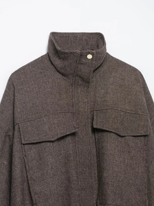 Detail of herringbone wool bomber jacket with stand collar and gold metal button