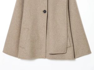 Detailed close-up of wool coat featuring camel fabric texture, black button and side pocket