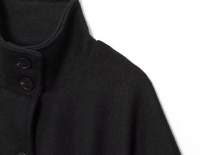 Dettaglio dell'elegante mantella nera con collo alto e bottoni in resina neri