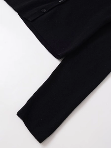 Detailed close-up of a black knit cardigan showing fine texture and matching black buttons