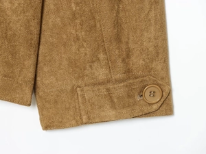 Detailed close-up of brown suede jacket cuff with button strap and fine stitching