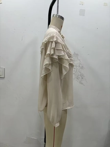 Detail of elegant beige chiffon shirt featuring layered ruffle sleeves and a stand collar