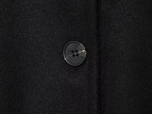 Dettaglio macro del tessuto in lana nera del mantello e bottone con trama marmorizzata