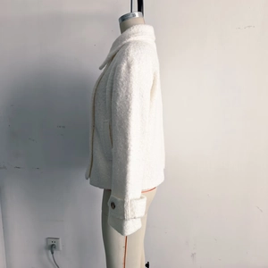 Detailed close-up of a white bouclé jacket collar and sleeve with adjustable button cuff