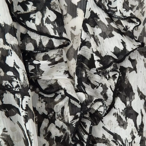 Fashionable mini dress featuring black and white abstract print and tiered ruffles with belt
