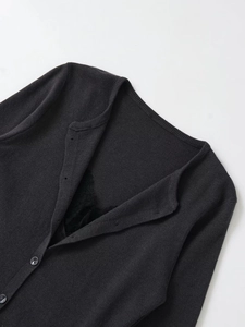 Close-up of black knit cardigan featuring delicate lace trim and round button details