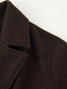 Detailed close-up of dark brown wool coat lapel with premium cashmere texture and stitching