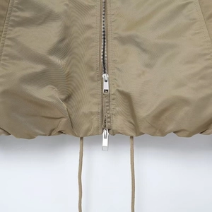 Detail of khaki jacket featuring silver double zipper and adjustable drawstring hem