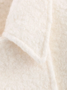 Macro shot of white boucle wool fabric texture and stitching detail on coat lapel