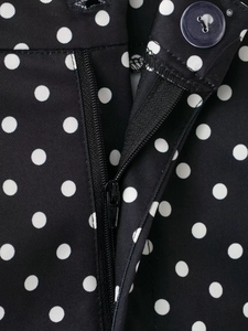 Détail macro de la fermeture éclair et du bouton sur le short noir à pois blancs