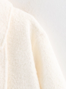 Macro shot of white boucle wool fabric showing detailed curly fiber texture and soft material