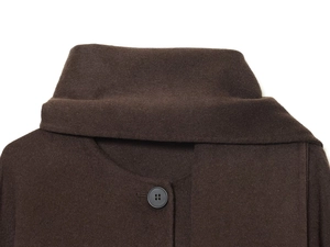 Detail of a dark brown wool coat collar with overlap design and black button texture