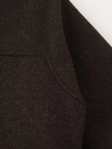 Detailed macro view of dark brown wool fabric texture and stitching on a winter coat