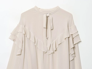 Detail of elegant beige chiffon blouse with layered ruffles and neck tie ribbon