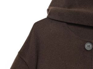 Close-up of dark brown wool coat collar showing button detail and textured fabric