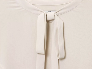 Close-up of beige blouse neck featuring round collar and elegant layered bow tie detail