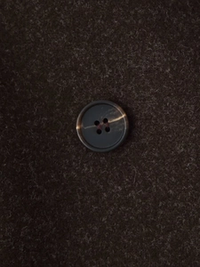 Macro shot of dark brown wool coat fabric texture and marbled four-hole button detail