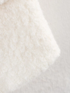 Detailed close-up of soft white bouclé texture and curly fleece fabric on a winter coat