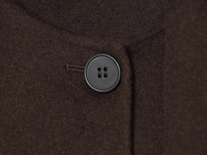 Close-up of thick dark brown wool fabric with detailed stitching and black resin button