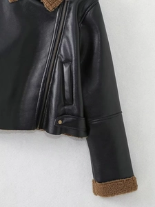 Detail of black faux leather biker jacket featuring brown sherpa lining and metal zipper