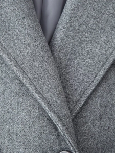 Detail of grey wool coat notched lapel with professional stitching and melange texture