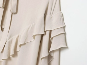Close-up of cream blouse showing layered ruffle details and textured crepe fabric