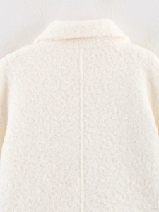 Detailed macro view of the cream boucle wool texture and stitching on the collar and back