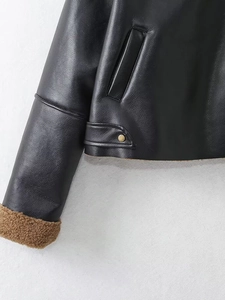 Close-up of black leather jacket showing brown faux shearling lining and pocket detail