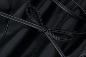 Gros plan d'un manteau en fausse fourrure noire avec nœud en cuir et lacets élégants