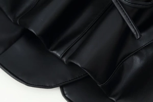 Détails de manteau en similicuir noir avec des coutures fines et une texture plissée