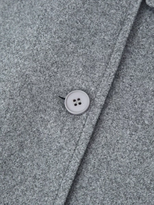 Detail of grey wool coat texture with a matching four-hole button and neat stitching