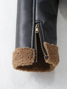 Close-up of black leather jacket cuff with thick brown faux shearling lining and metal zipper