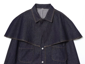 Detail of dark blue denim cape jacket showing collar, size M label and silver buttons