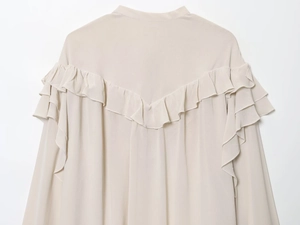Detail of light beige chiffon shirt featuring a V-shaped layered ruffle back and stand collar