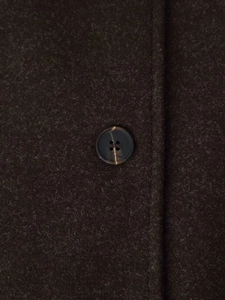 Detailed macro view of dark brown wool fabric texture and marble-patterned resin button