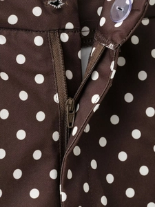 Détail du short à pois avec fermeture éclair et bouton en plastique translucide