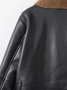 Detail shot of black leather jacket shoulder with premium brown faux shearling lining