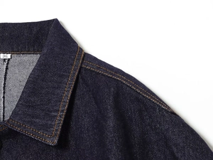Close-up of indigo denim jacket collar with orange contrast stitching and size M label